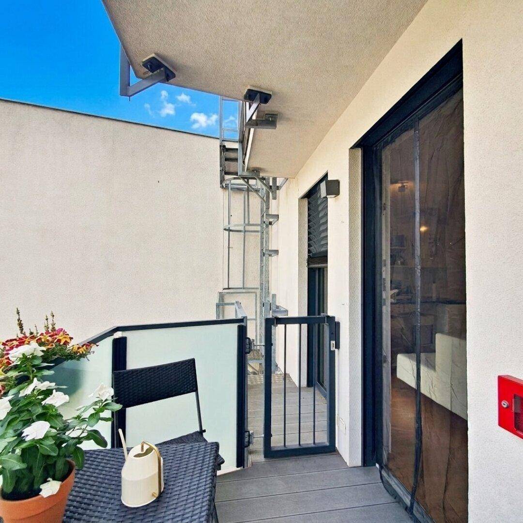 Balkon mit modernem Sichtschutz und Blick auf die Gebäudefassade sowie eine Außentreppe.