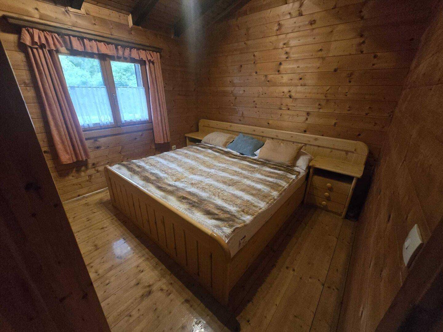 Schlafzimmer mit Doppelbett, Holzwänden und Holzboden, bietet eine gemütliche Atmosphäre.