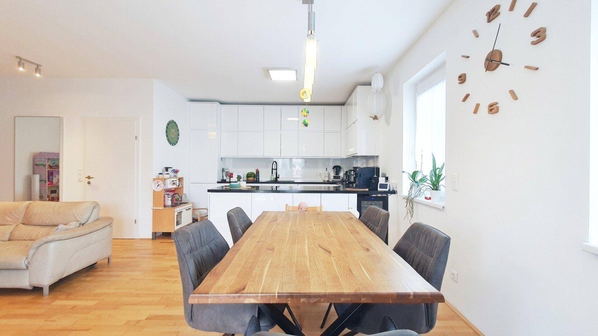Heller offener Wohn-Essbereich mit moderner Küche und Holzboden.