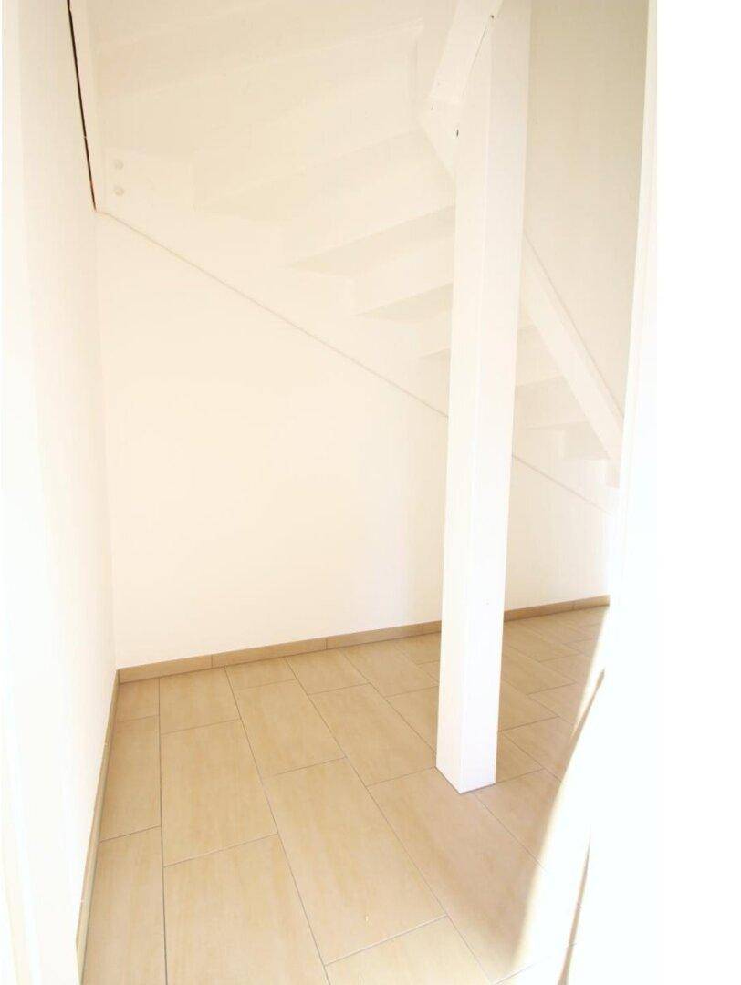 Praktischer Stauraum unter der Treppe mit Fliesenboden.