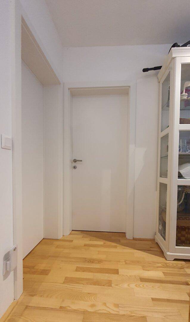 Heller Flur mit Holzboden und einer weißen Vitrine.