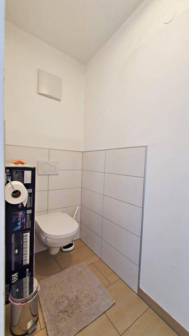 Kleines Gäste-WC mit wandhängender Toilette und Fliesenboden.