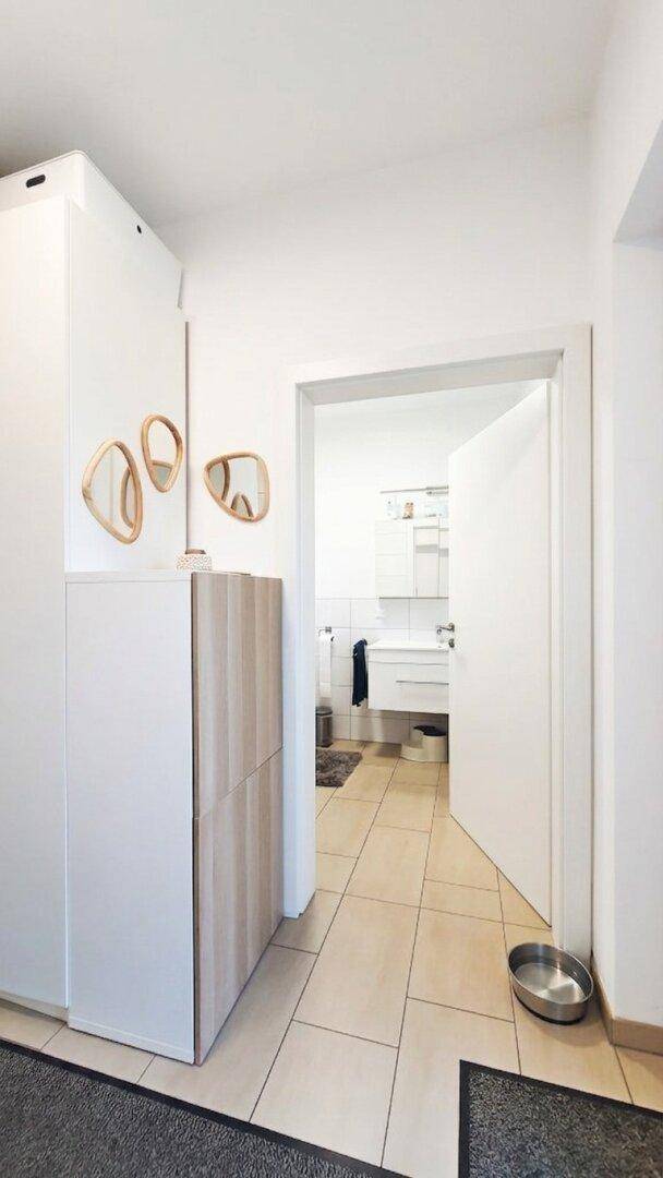 Heller Flur mit Fliesenboden und Zugang zu einem modernen Badezimmer.