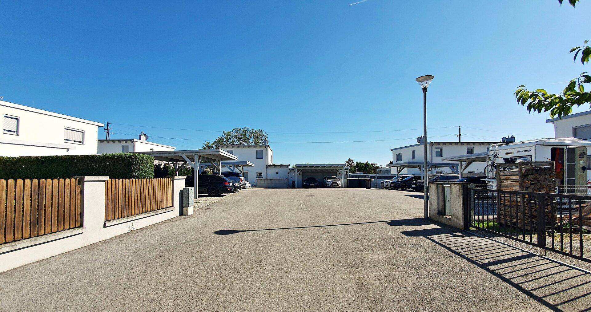 Zufahrt zu einer Wohnanlage mit Parkplätzen und Carports.