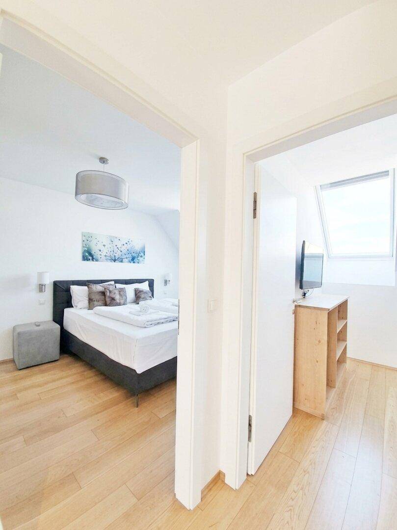 Flur mit Blick in zwei helle Schlafzimmer, beide ausgestattet mit Holzboden und Dachfenstern.