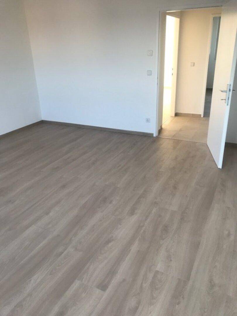 Geräumiges Zimmer mit hellem Laminatboden und weißen Wänden, ideal für individuelle Gestaltung.