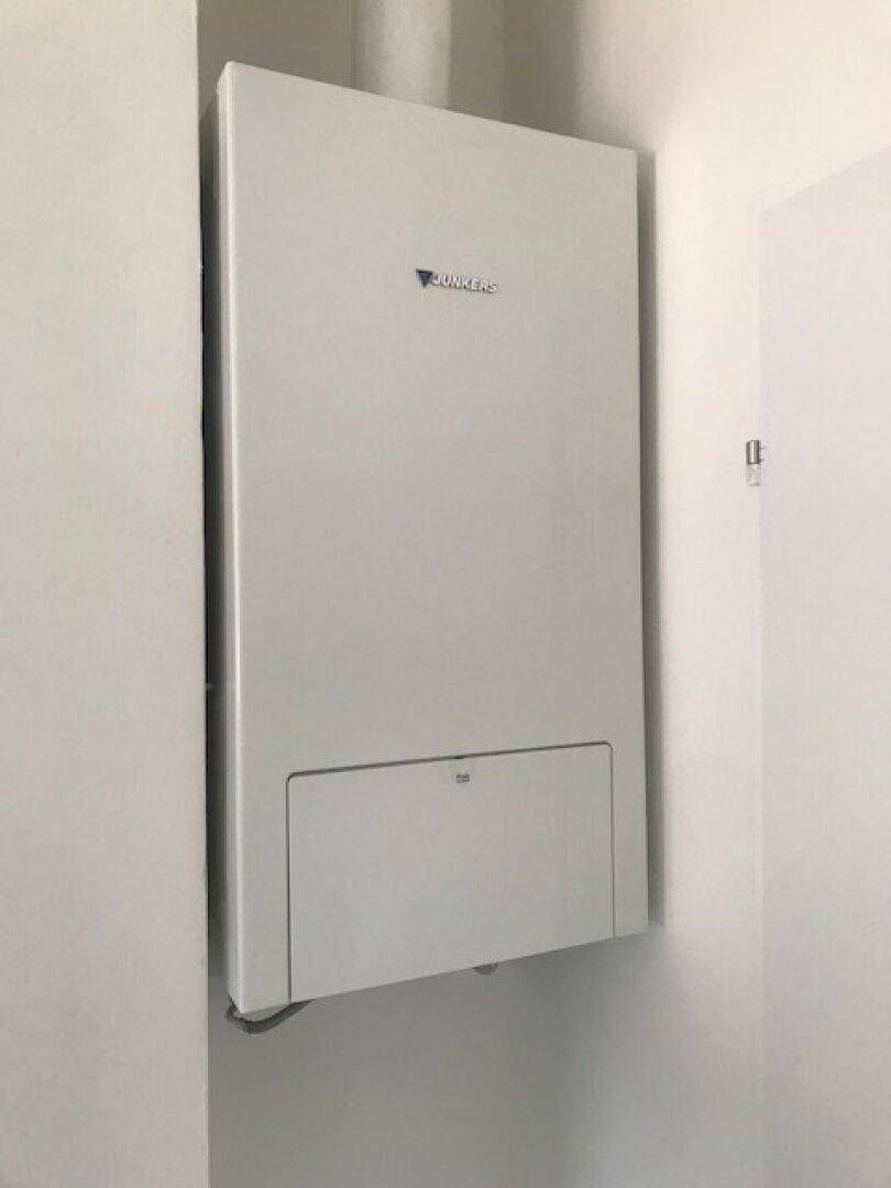 Wandmontierte Heizungsanlage der Marke Junkers in einem sauberen Technikraum.