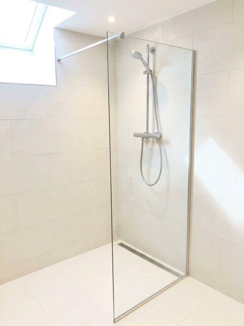 Modernes Badezimmer mit ebenerdiger Dusche, Glasabtrennung und hellen Fliesen.