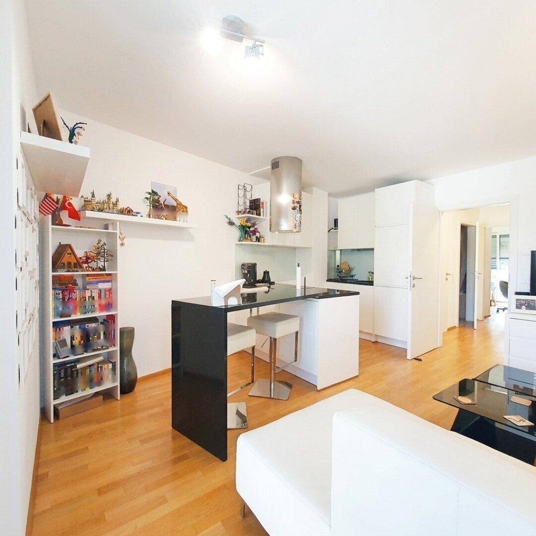 Offener Wohnbereich mit integrierter Küche, Holzboden und moderner Einrichtung.