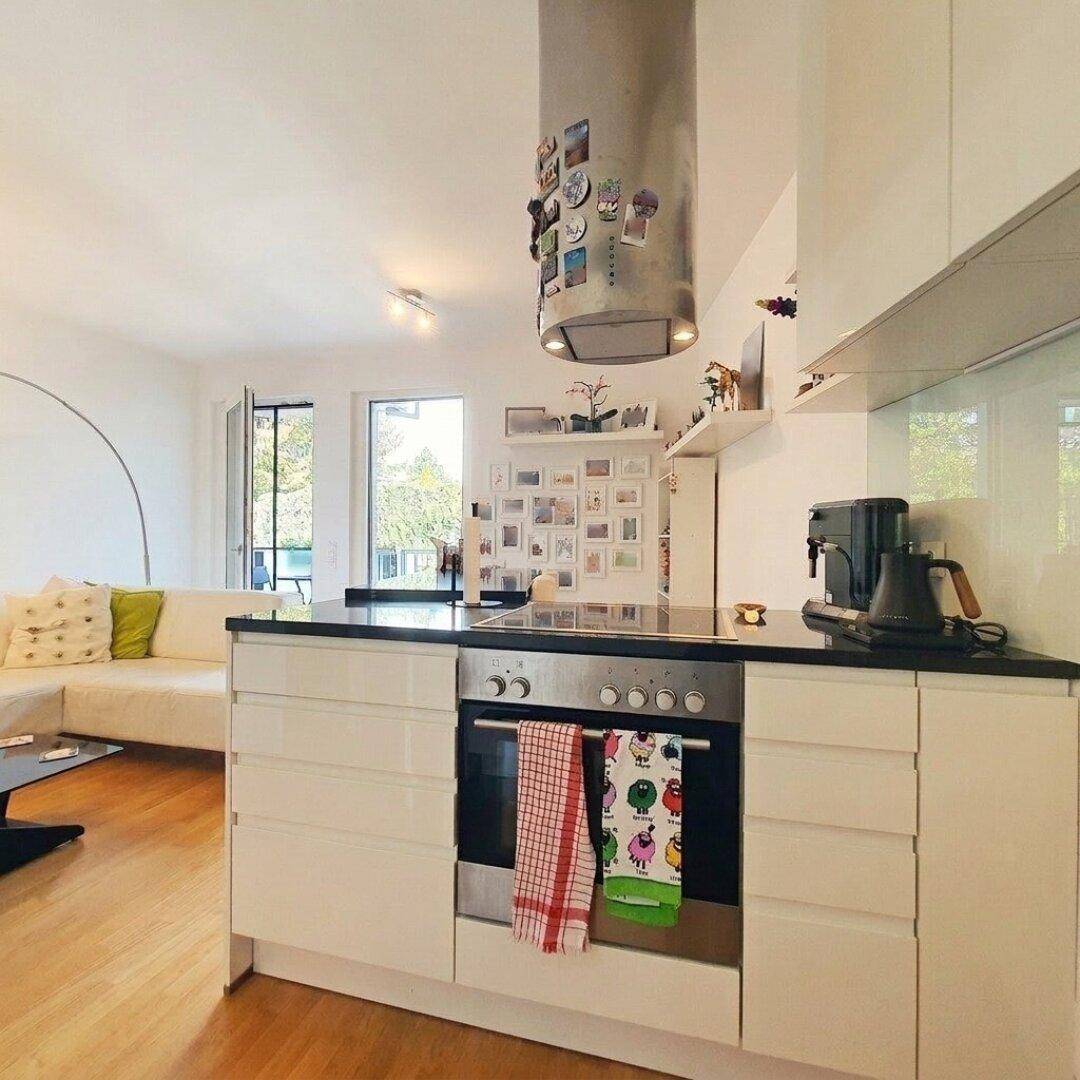 Moderne Einbauküche mit Kochinsel, integriertem Backofen und Dunstabzugshaube.