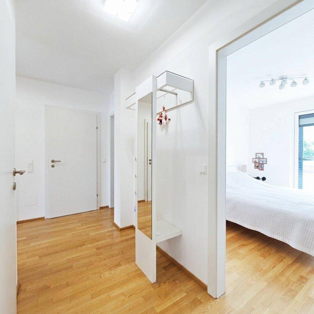 Heller Flur mit Holzboden und Garderobe, der zu den Schlafzimmern führt.