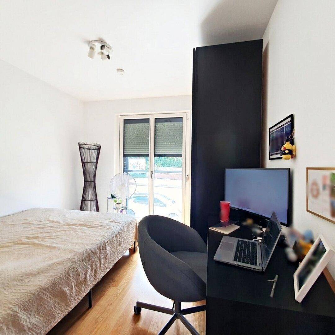 Schlafzimmer mit Einzelbett, Schreibtisch und Zugang zu einem Außenbereich.