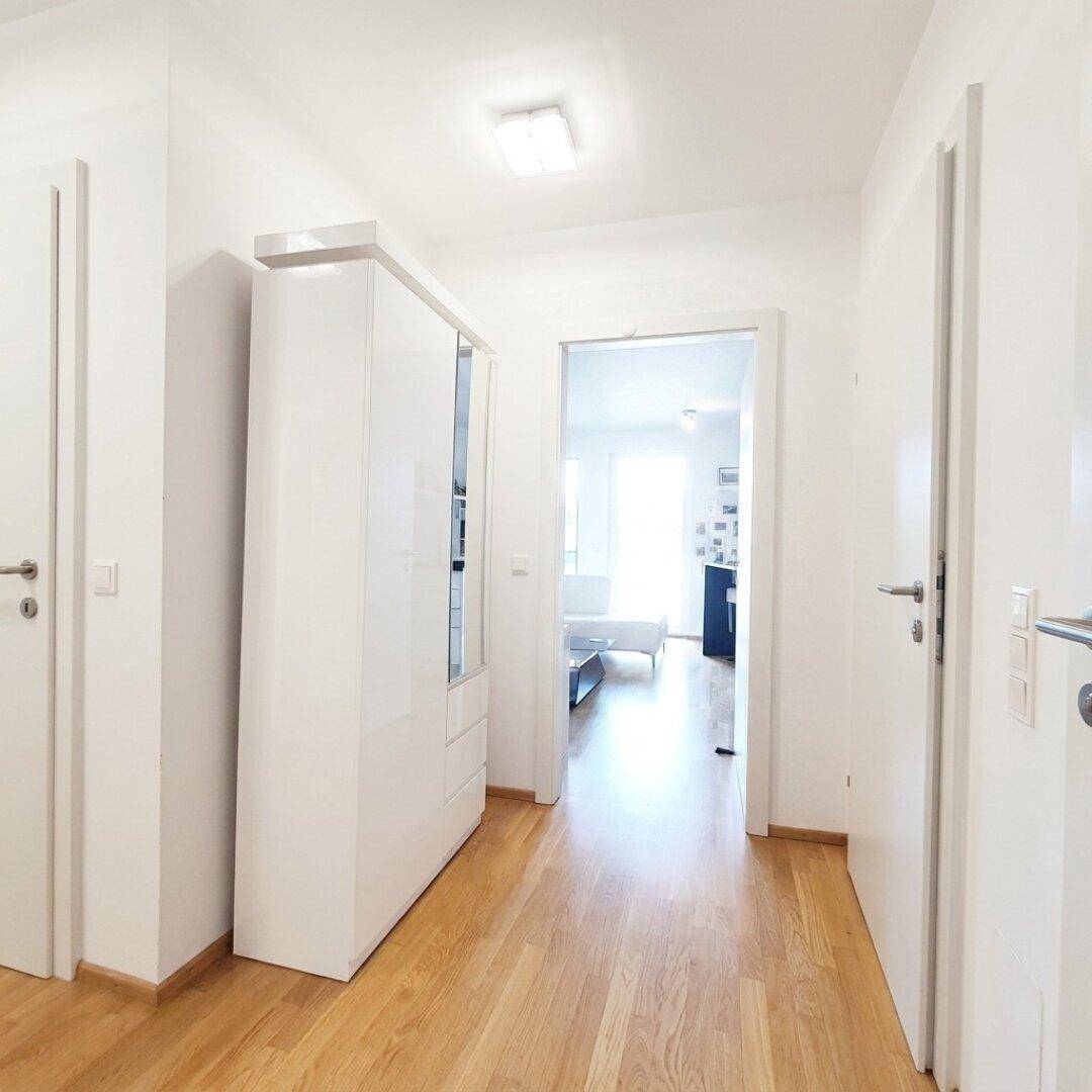 Geräumiger Flur mit Holzboden und weißem Schrank, der zu den Wohnbereichen führt.