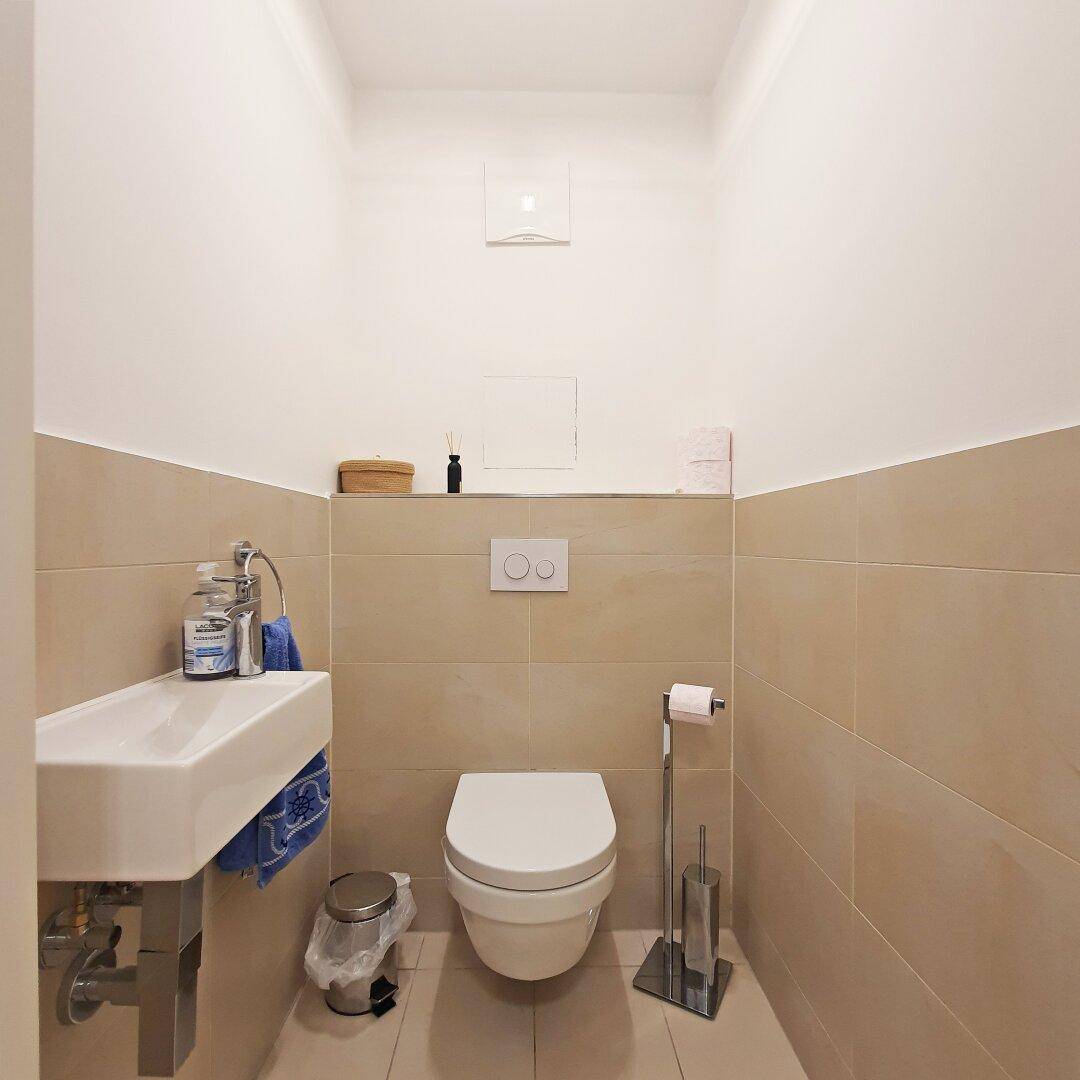 Separates Gäste-WC mit wandhängender Toilette und kleinem Waschbecken.