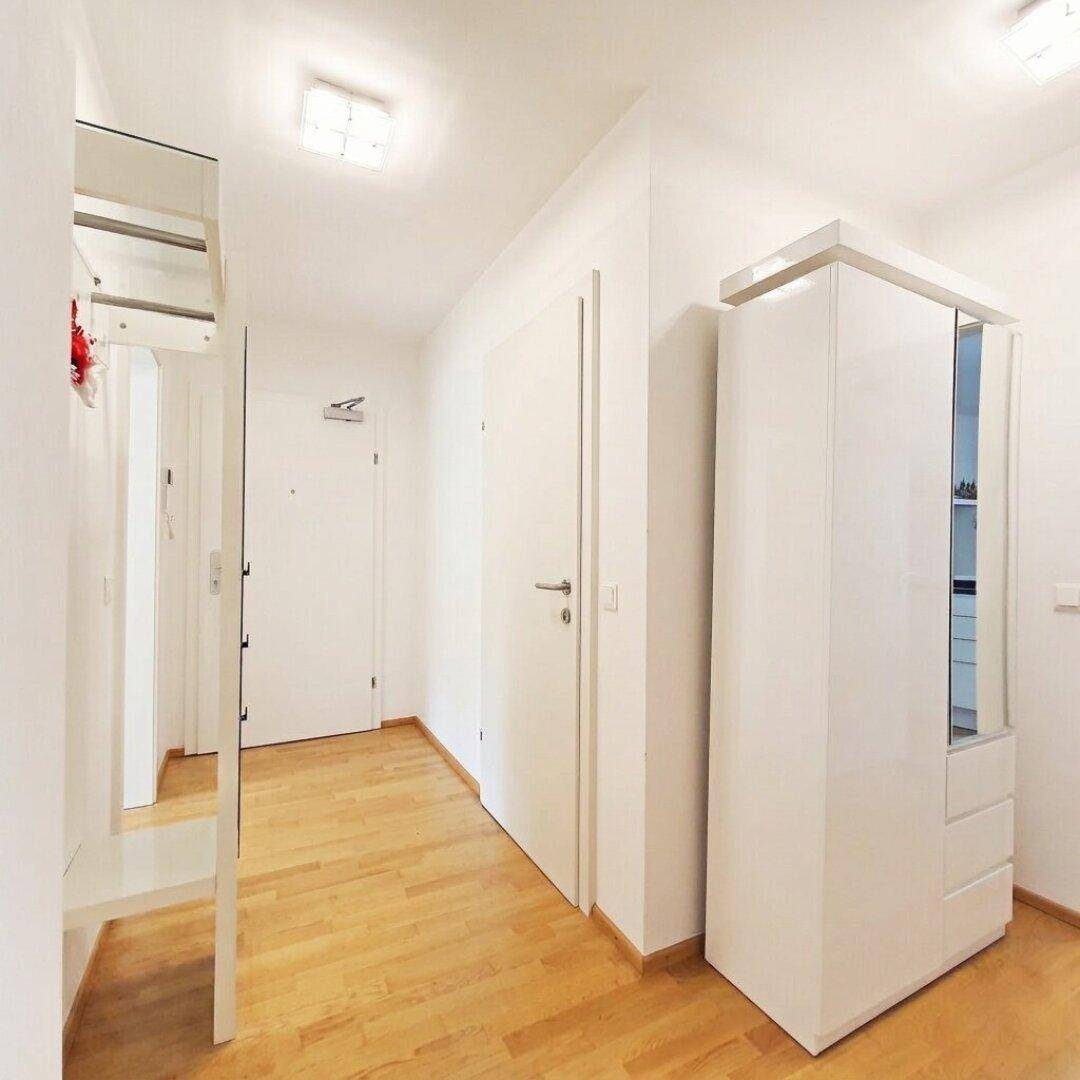 Heller Flur mit Holzboden und Garderobe, der zu den Wohnbereichen führt.