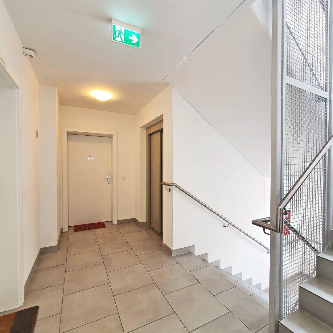 Heller Treppenhausbereich mit Fliesenboden und Aufzug, bietet Zugang zu den Etagen.