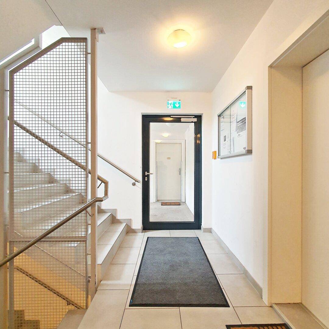 Eingangsbereich mit Fliesenboden, Treppenhaus und Aufzug, hell und funktional gestaltet.