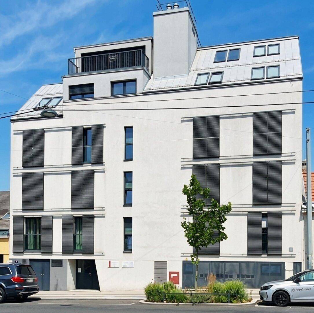 Moderne Gebäudefassade mit vielen Fenstern und Jalousien, in einem städtischen Umfeld.