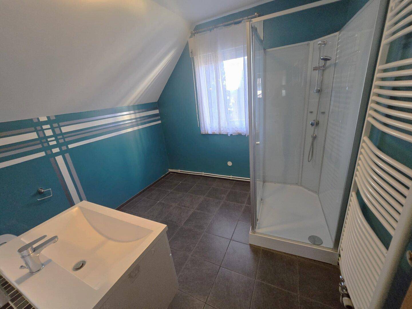 Badezimmer im Dachgeschoss mit Dusche, Waschbecken und beheiztem Handtuchhalter.