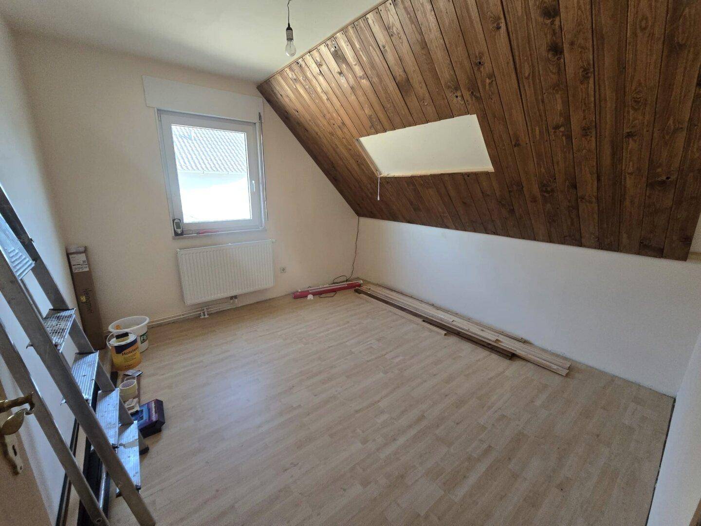 Dachgeschosszimmer mit Holzdecke, Laminatboden und Fenster, ideal als Kinderzimmer.