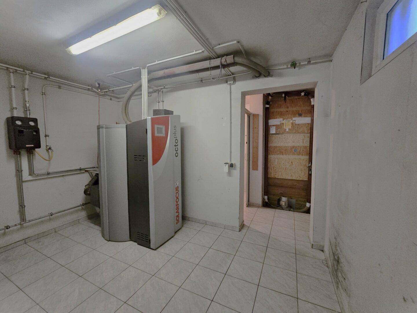 Heizungsraum im Keller mit moderner Pelletheizung und Versorgungsleitungen.