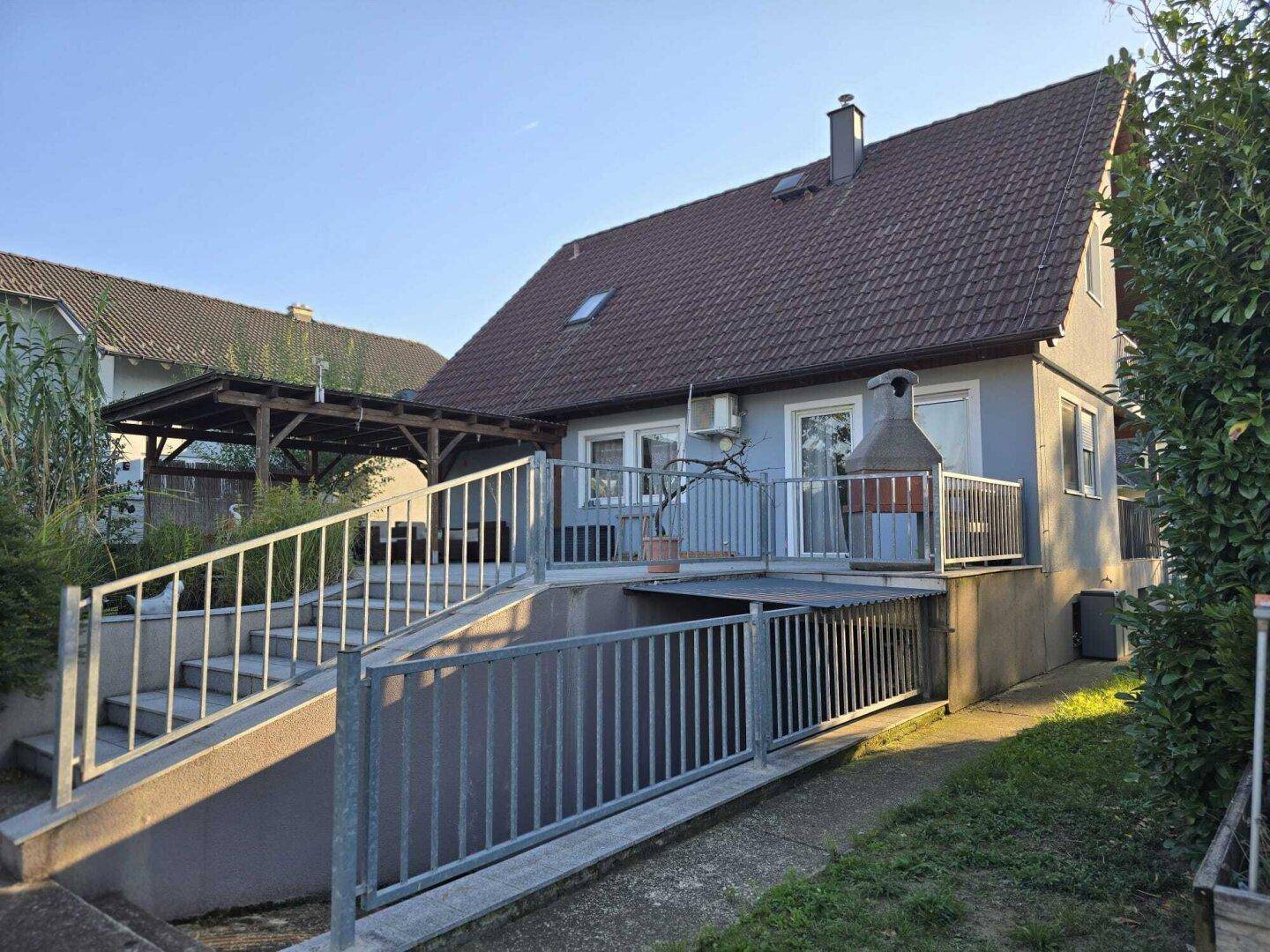 Rückseite des Hauses mit großer Terrasse, Außentreppe und Grillbereich.