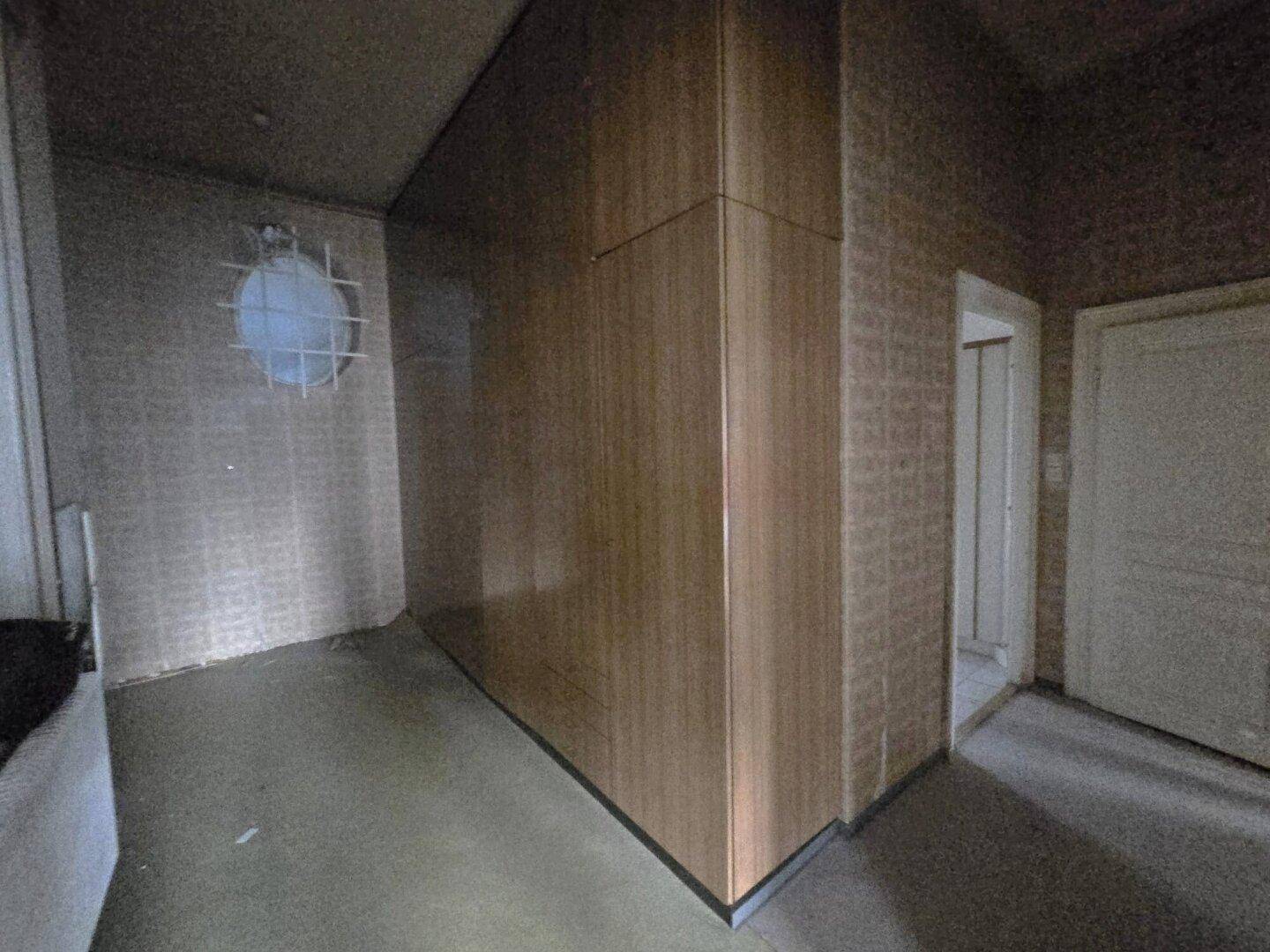 Flur mit Holzverkleidung und einem runden Fenster, bietet integrierten Stauraum.