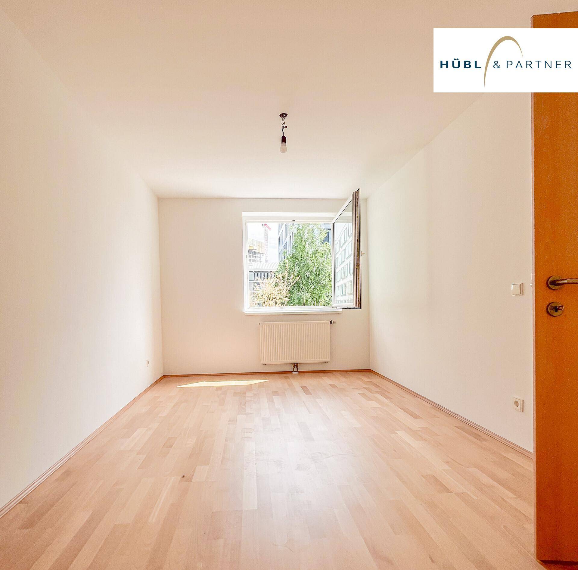 Helles Schlafzimmer mit Parkettboden und einem Fenster, das den Raum gut belichtet.