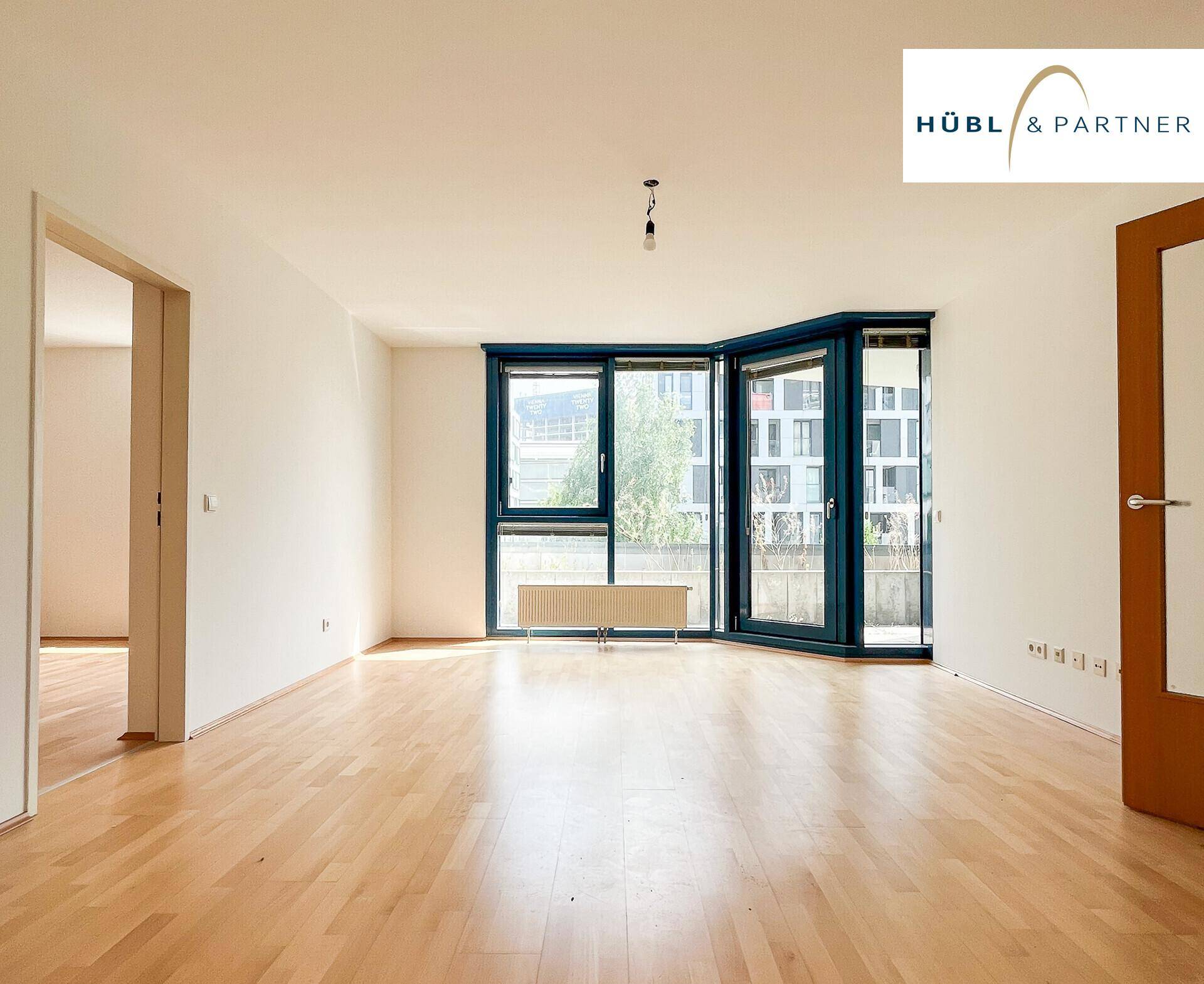 Helles Wohnzimmer mit Parkettboden und großen Fenstern, die viel Tageslicht hereinlassen.