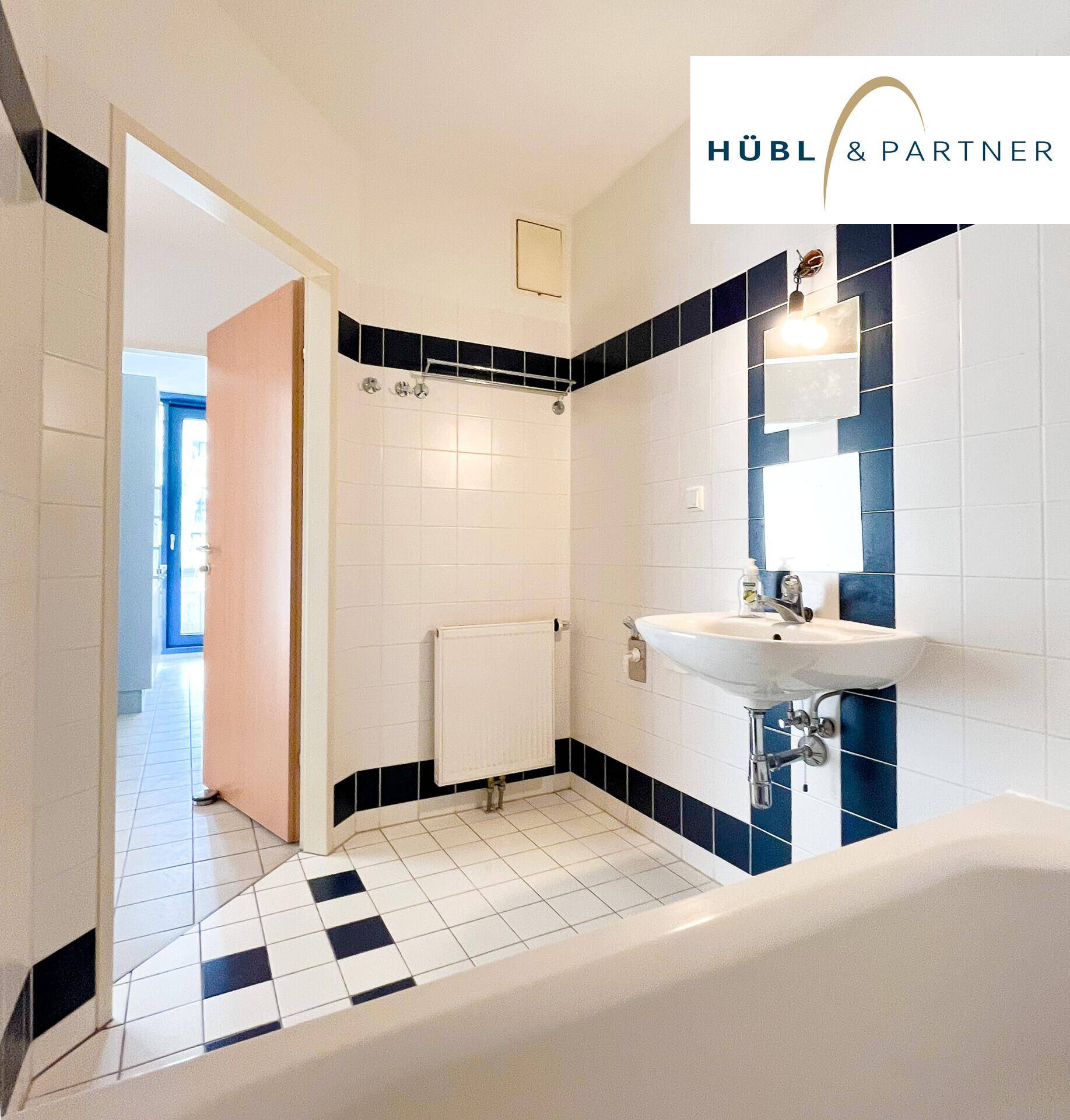 Badezimmer mit weiß-blauen Fliesen, Waschbecken und Badewanne, im klassischen Stil.