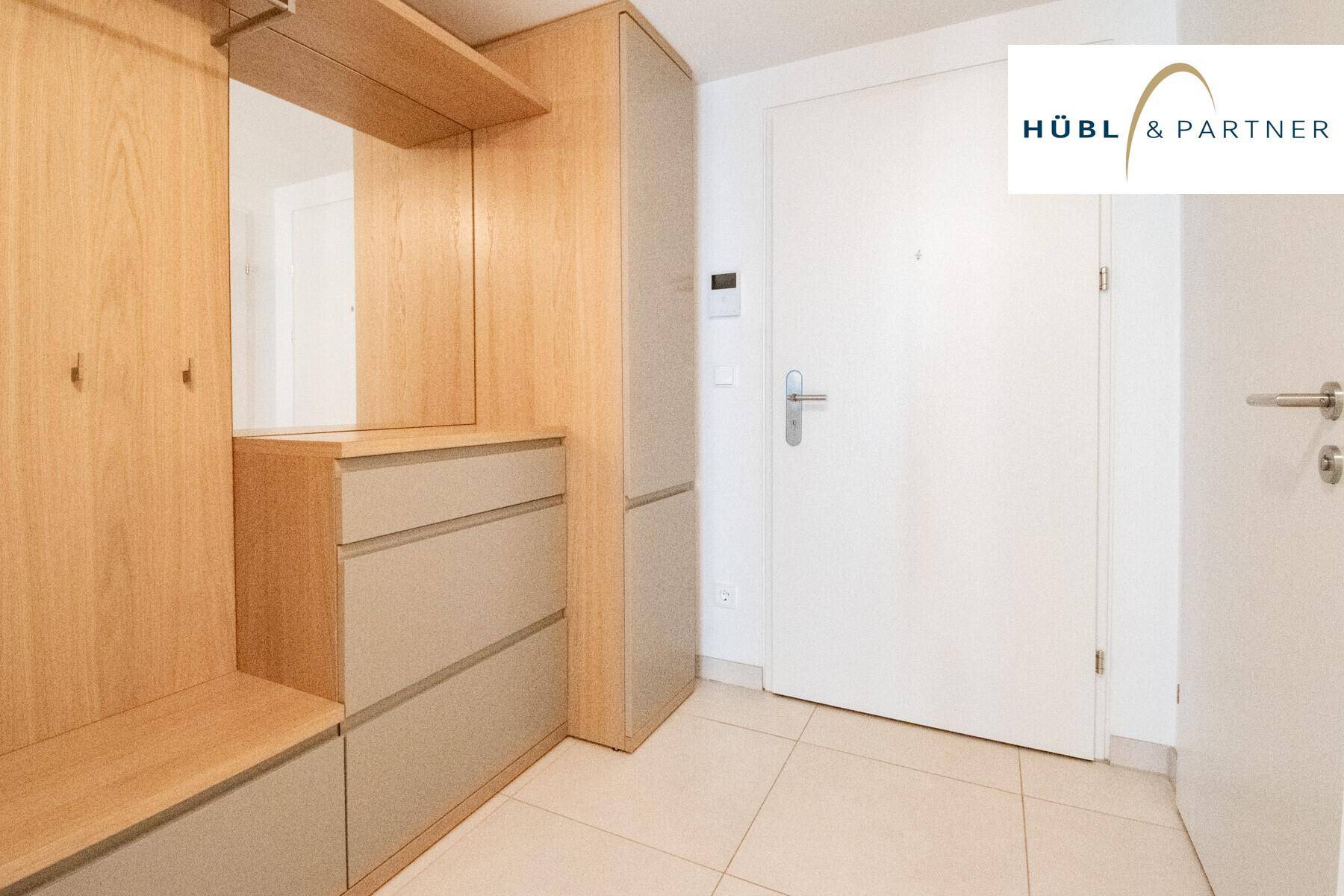 Eingangsbereich mit praktischen Einbauschränken aus Holz und hellem Fliesenboden.