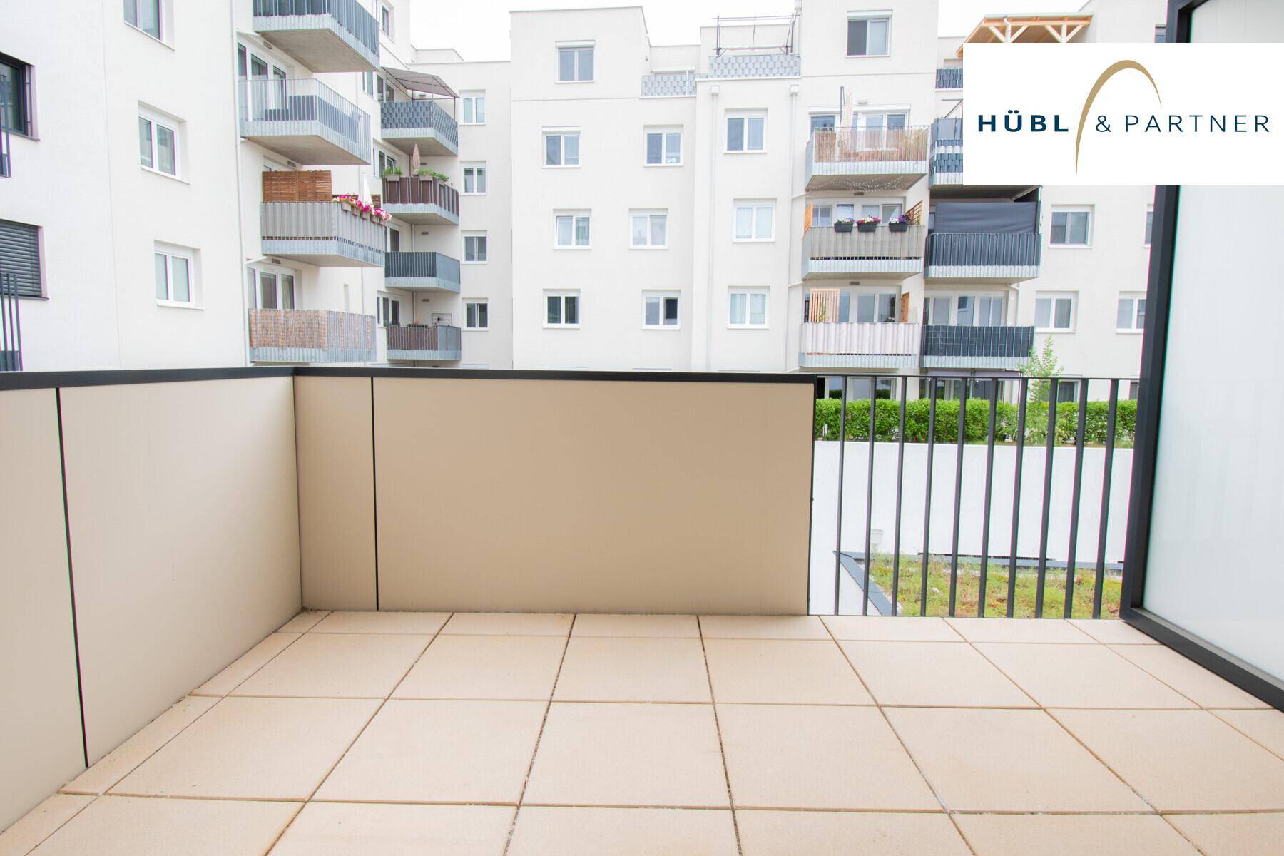 Balkon mit Fliesenboden und Blick auf die umliegenden modernen Wohngebäude.