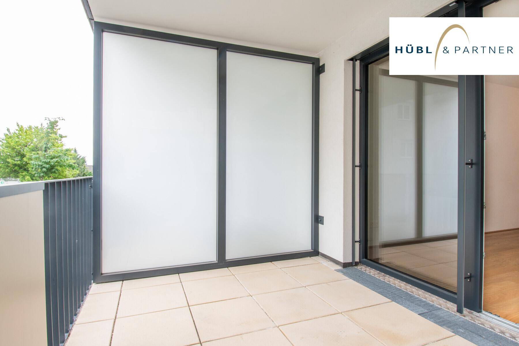 Heller Balkon mit Fliesenboden und undurchsichtigen Glaspaneelen für mehr Privatsphäre.