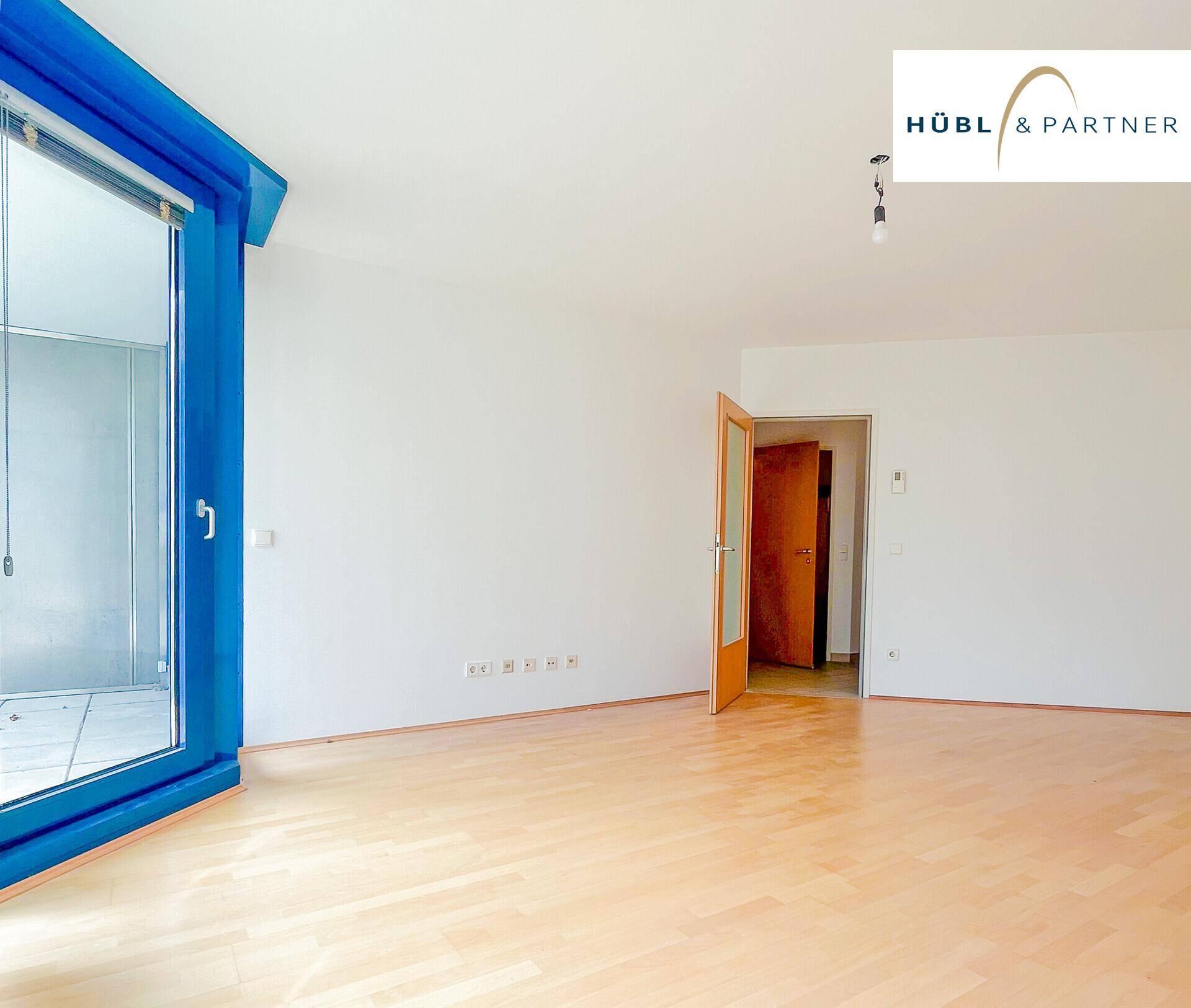 Geräumiges Wohnzimmer mit Holzboden und Zugang zu einem Außenbereich durch eine große Fenstertür.
