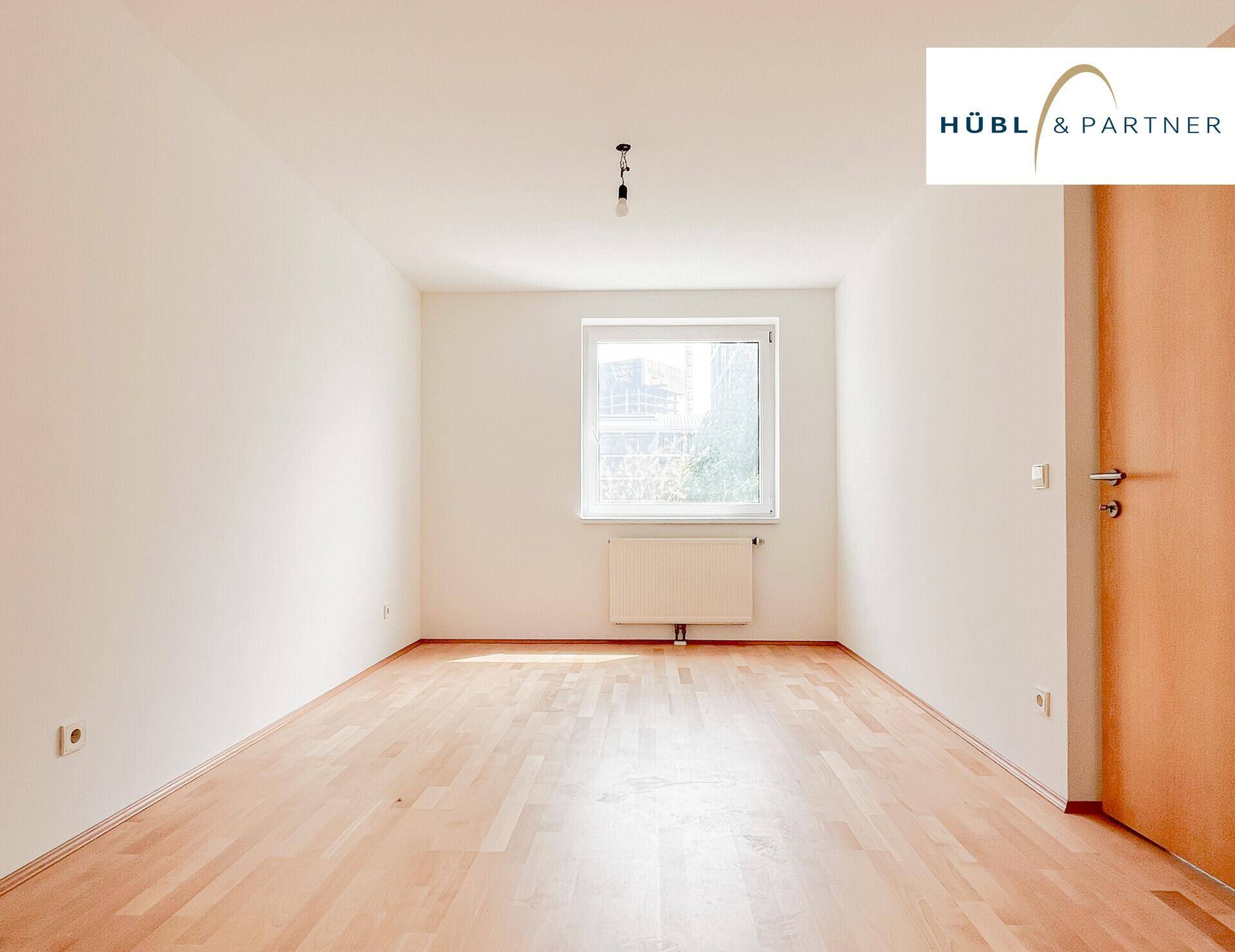 Leeres Zimmer mit Parkettboden und einem Fenster, das für natürliche Belichtung sorgt.