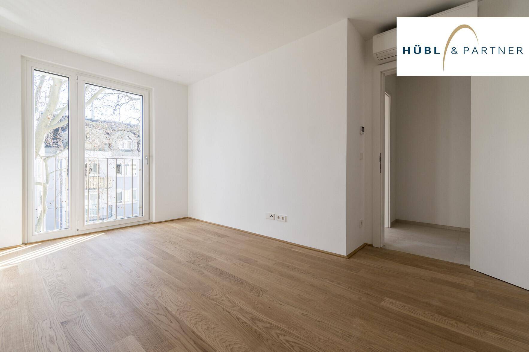 Geräumiges Schlafzimmer mit Parkettboden und französischem Balkon, bietet eine angenehme Wohnatmosphäre.