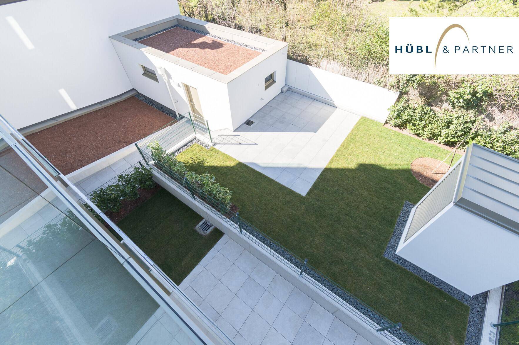 Gepflegter Gartenbereich mit Rasenfläche und gefliester Terrasse, ideal zum Entspannen im Freien.