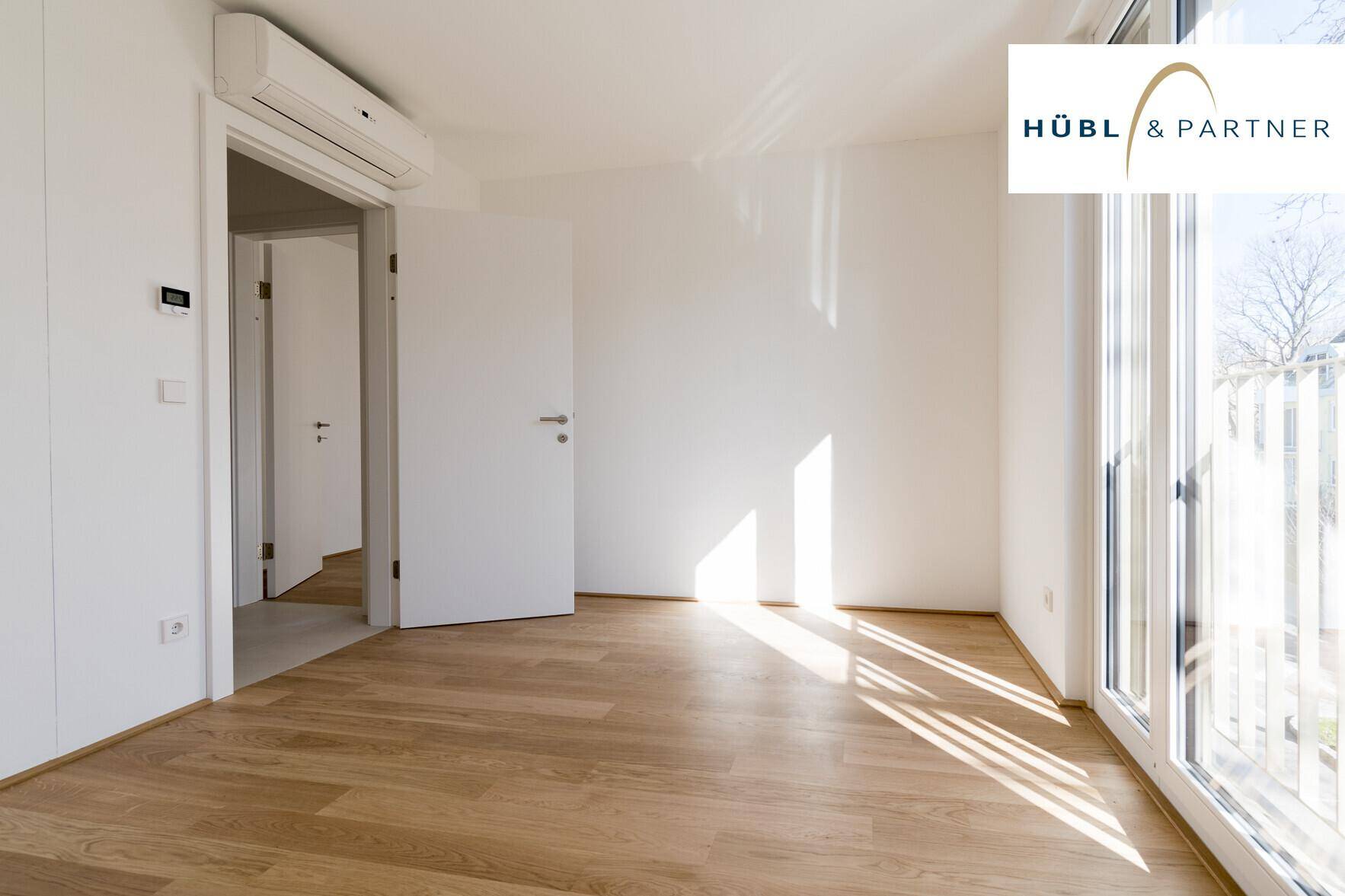 Sonniger Raum mit Parkettboden und Zugang zu einem französischen Balkon, ideal als Schlafzimmer.