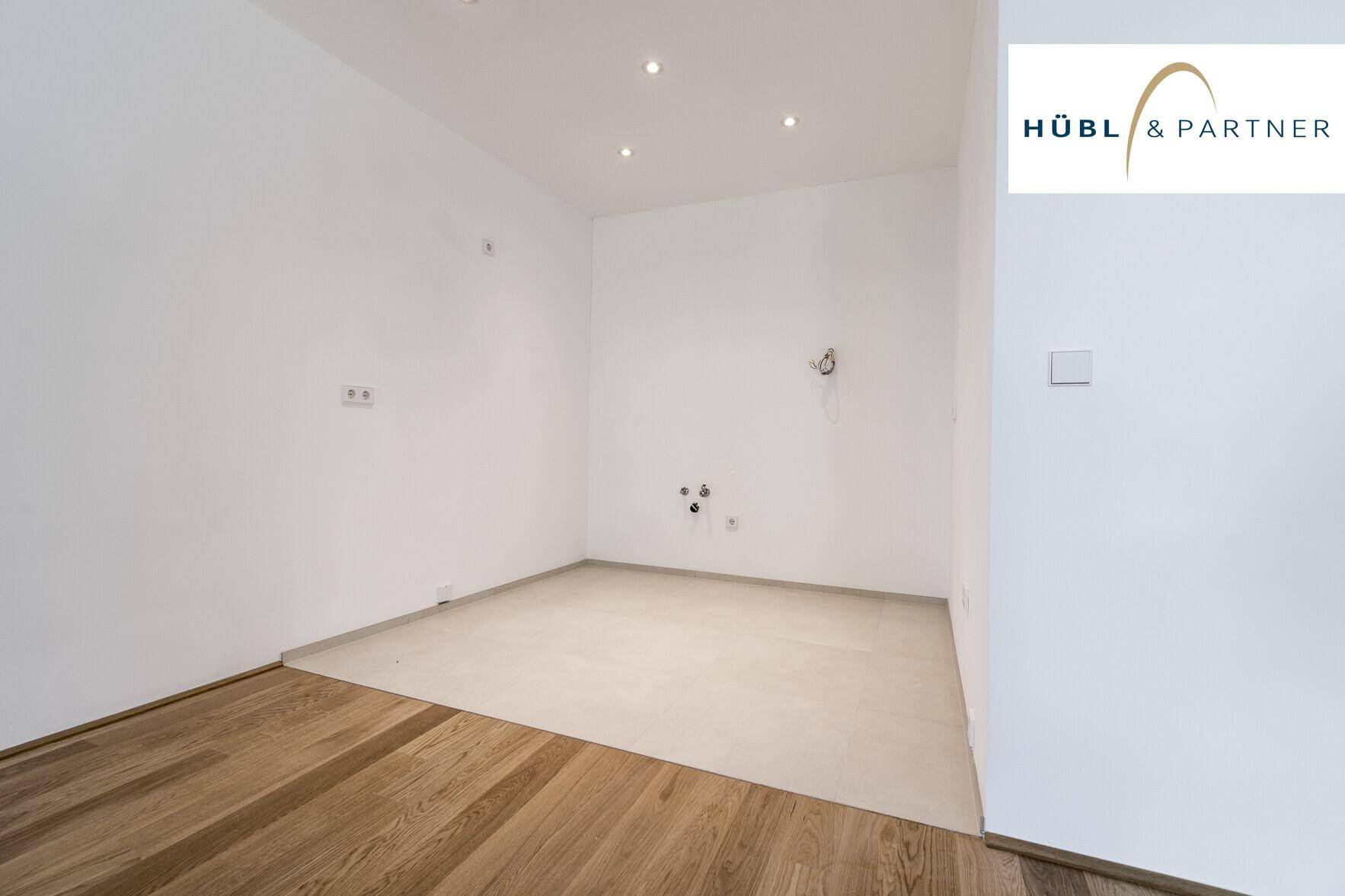 Vorbereiteter Küchenbereich mit Fliesenboden und Anschlüssen für eine moderne Einbauküche.