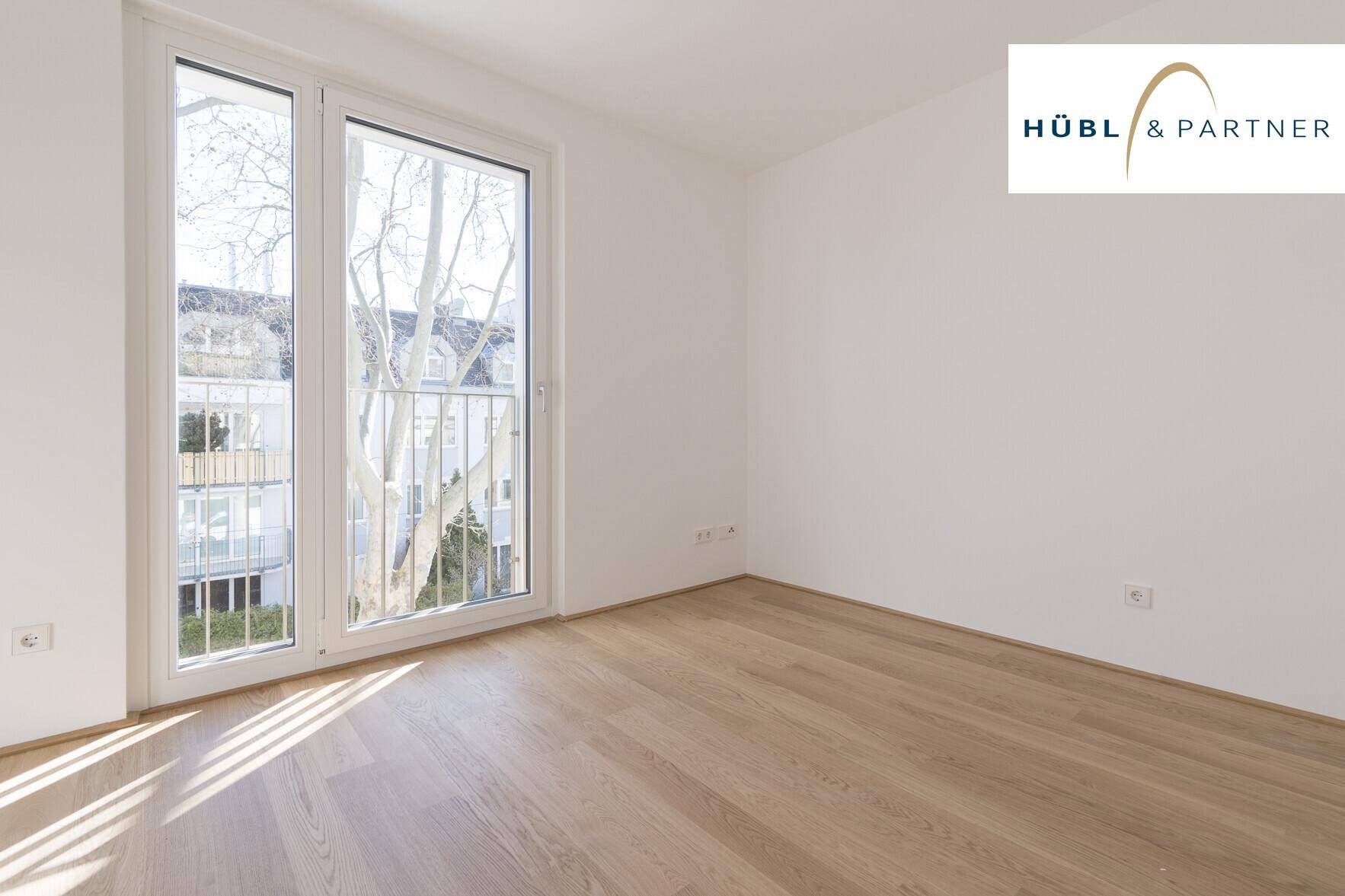 Helles Schlafzimmer mit Parkettboden und französischem Balkon bietet viel Tageslicht.
