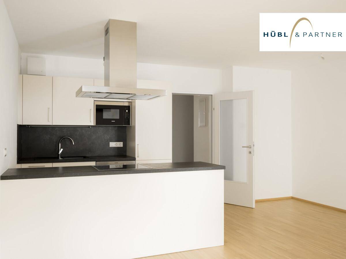 Moderne Einbauküche mit weißen Schränken, dunkler Arbeitsplatte, integrierter Mikrowelle und Kochinsel.