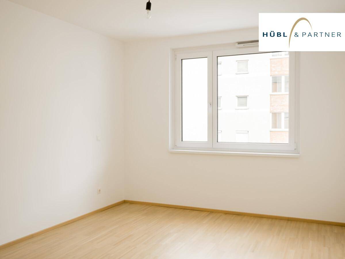 Helles Schlafzimmer mit großen Fenstern und Parkettboden, bereit zur individuellen Gestaltung.