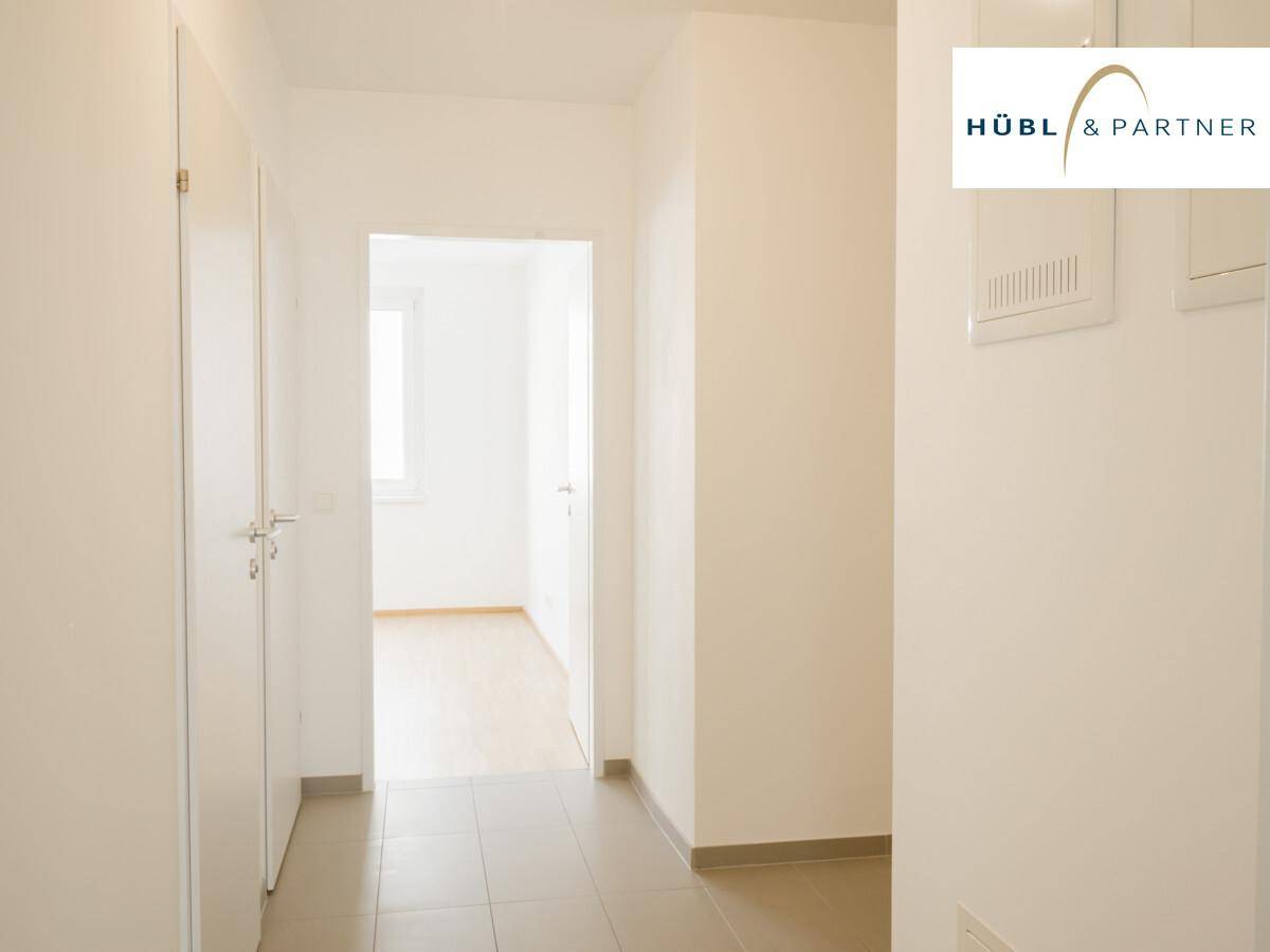 Heller Flur mit Fliesenboden und weißen Türen, der zu den verschiedenen Räumen der Wohnung führt.