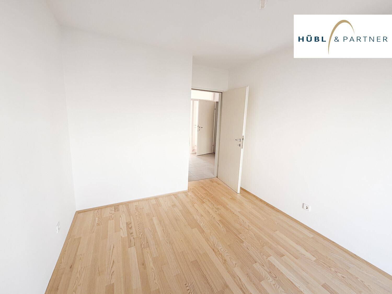Leeres Schlafzimmer mit hellem Parkettboden und weiß gestrichenen Wänden, bereit zur Einrichtung.