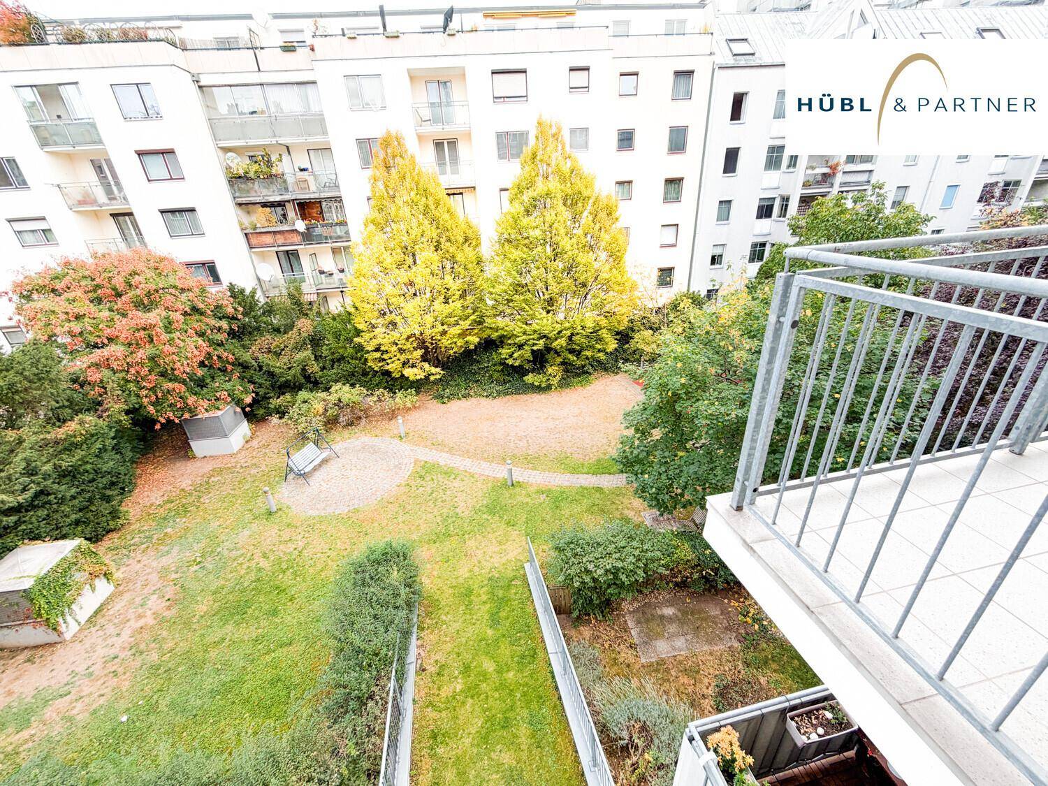 Balkon mit Blick auf den grünen Innenhof und die umliegenden Wohngebäude.