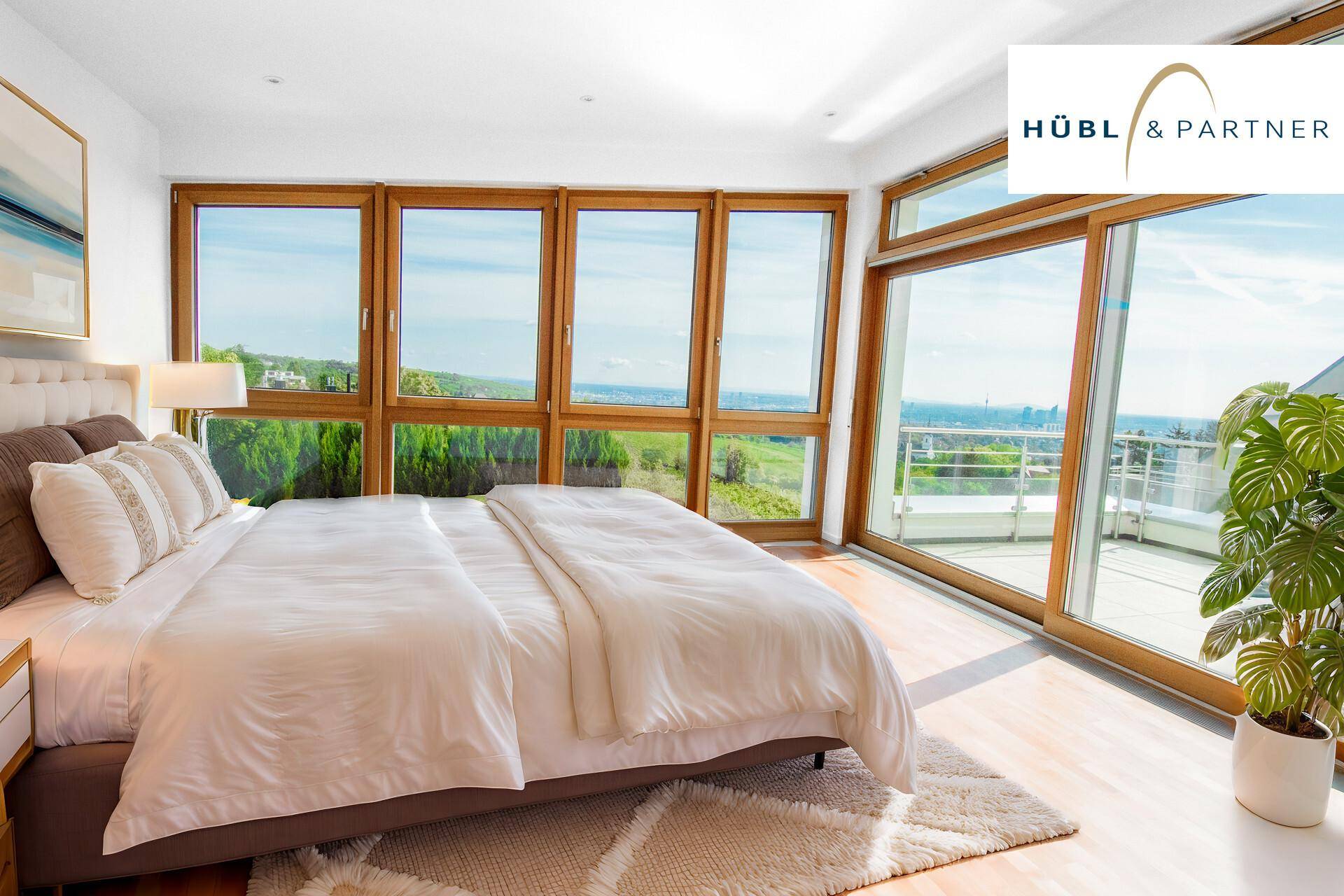 Helles Schlafzimmer mit großen Fenstern, Holzboden und Zugang zur Terrasse mit Weitblick.