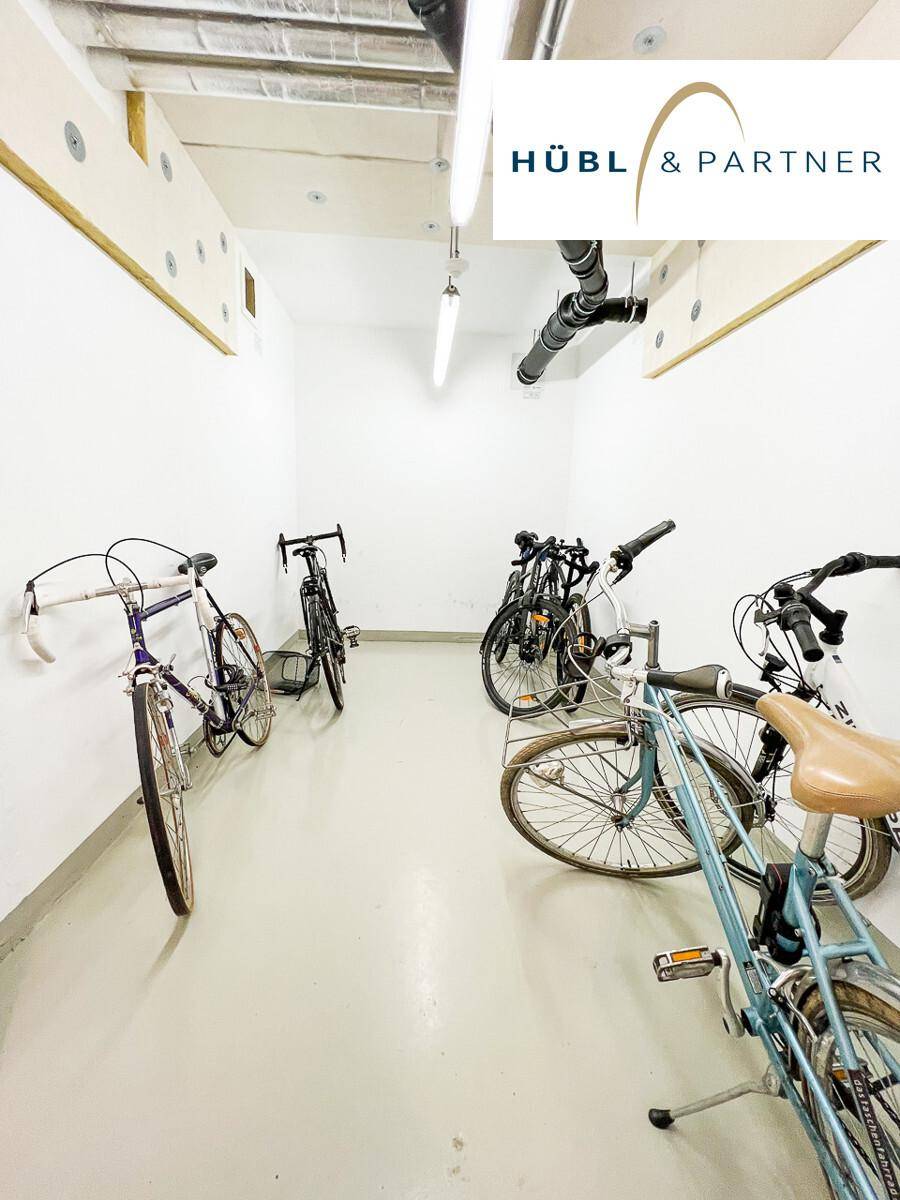 Heller Fahrradraum mit mehreren Fahrrädern und einfacher Beleuchtung.