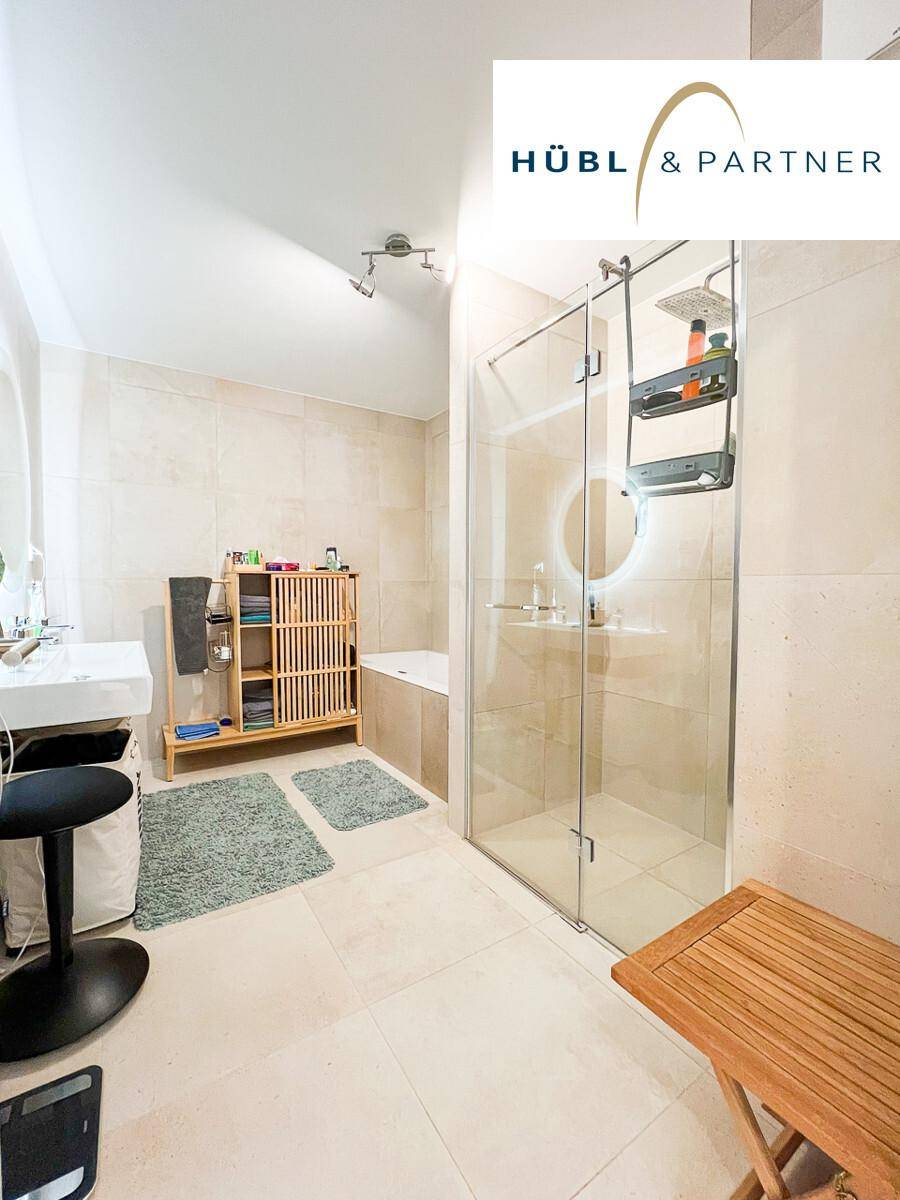 Modernes Badezimmer mit beigefarbenen Fliesen, begehbarer Dusche und Waschbecken.
