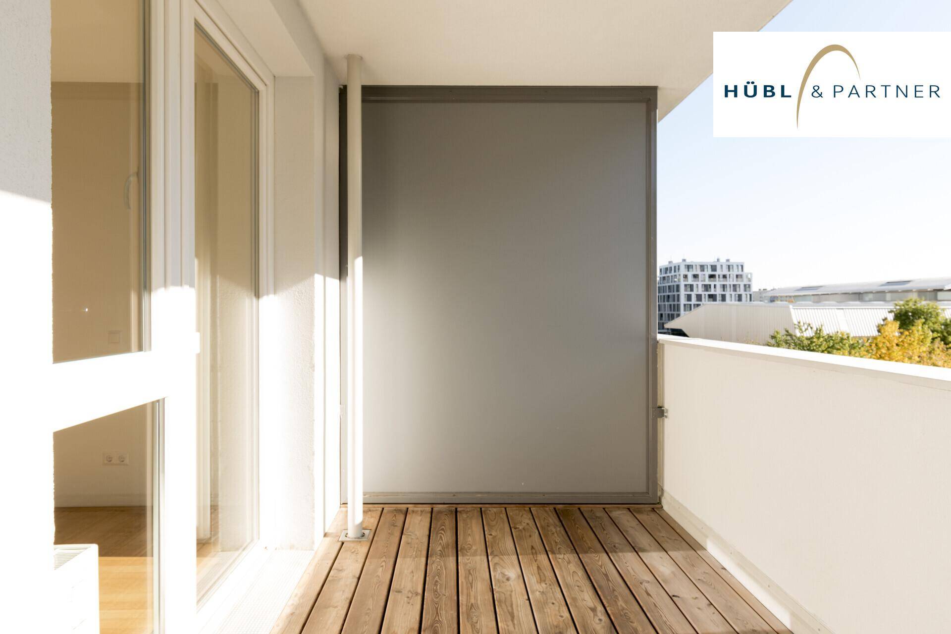 Heller Balkon mit Holzboden und einem Sichtschutz, ideal für entspannte Stunden im Freien.