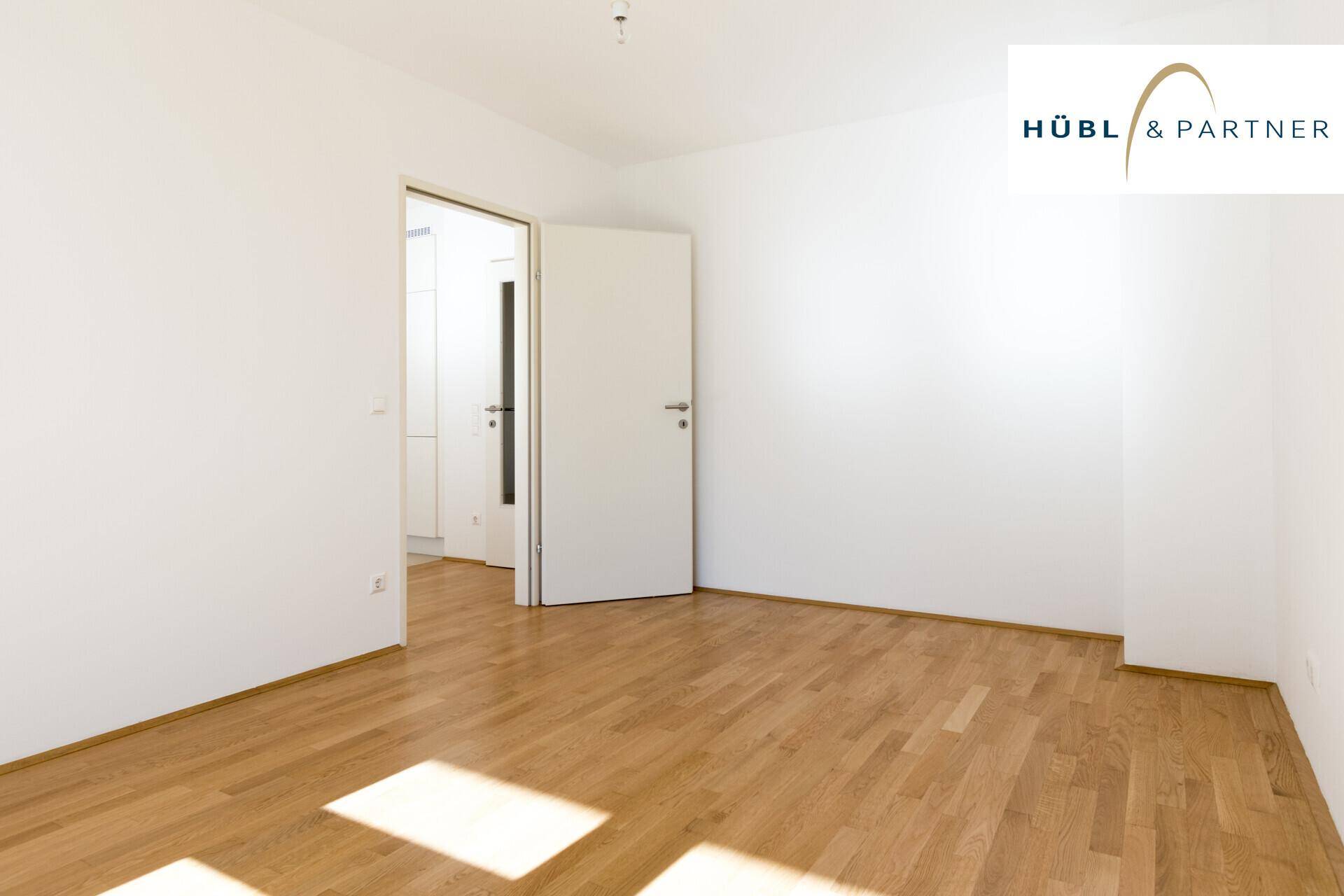 Leeres Zimmer mit hellem Holzboden und weiß gestrichenen Wänden, bereit zur individuellen Gestaltung.